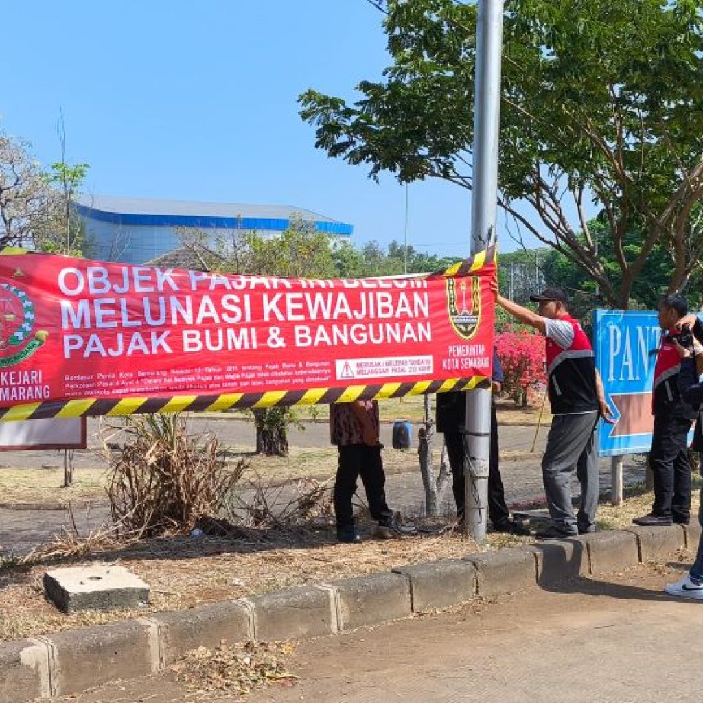Bapenda didampingi Kejaksaan Tinggi dan Satpol PP Kota Semarang memasang spanduk peringatan pelunasan PBB. Foto: Dok. Alan Henry
